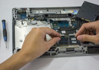Close-up of a technician assembling a laptop's internal components using tools.
