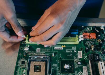 Hands carefully assembling a computer motherboard, showcasing technical craftsmanship in electronics.